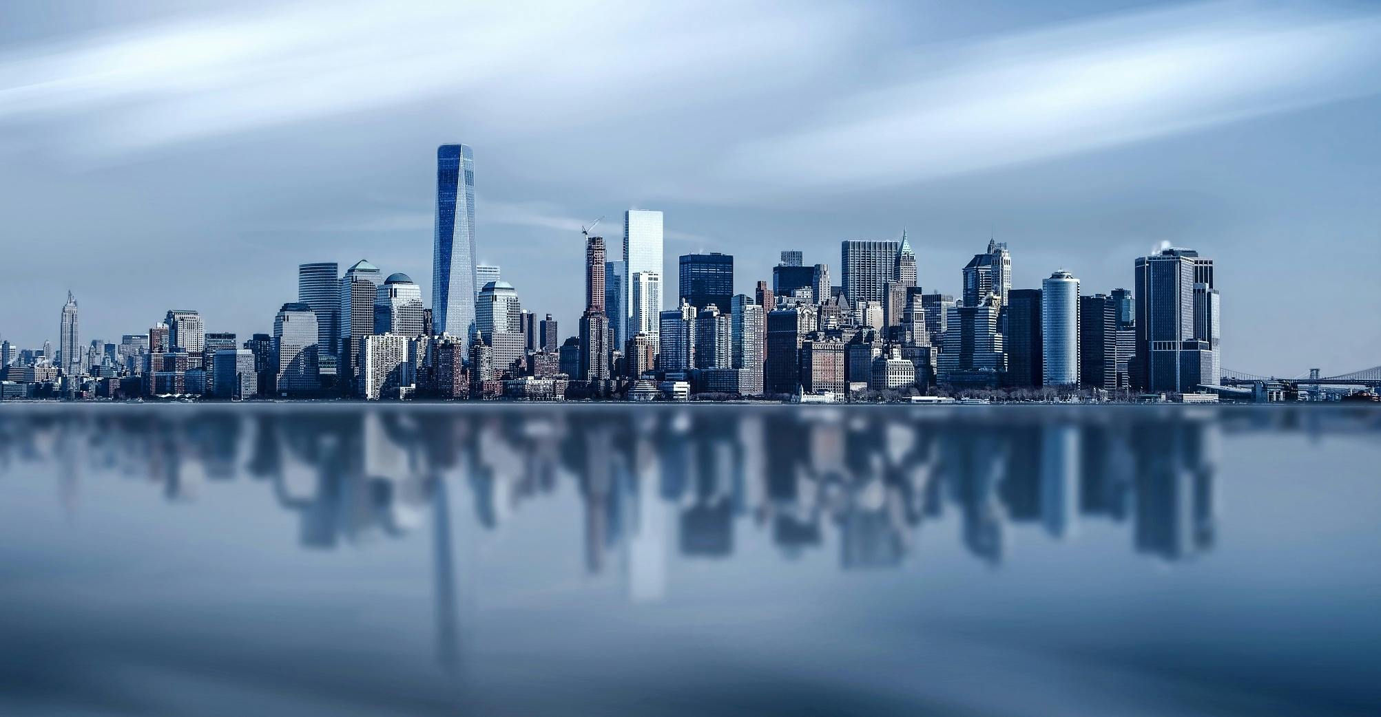 Stunning New York City skyline with modern skyscrapers reflecting on a calm river.